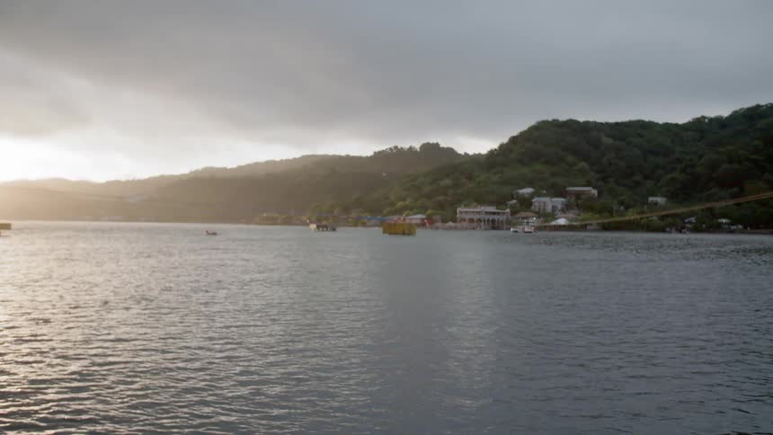 Boats sit in the water offshore from a coastal town