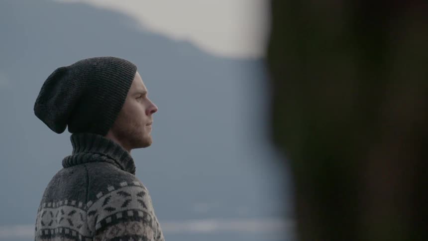 A man in a patterned sweater stands outside