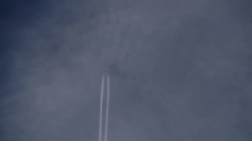 An airplane leaves a smoke trail as it flies across the sky