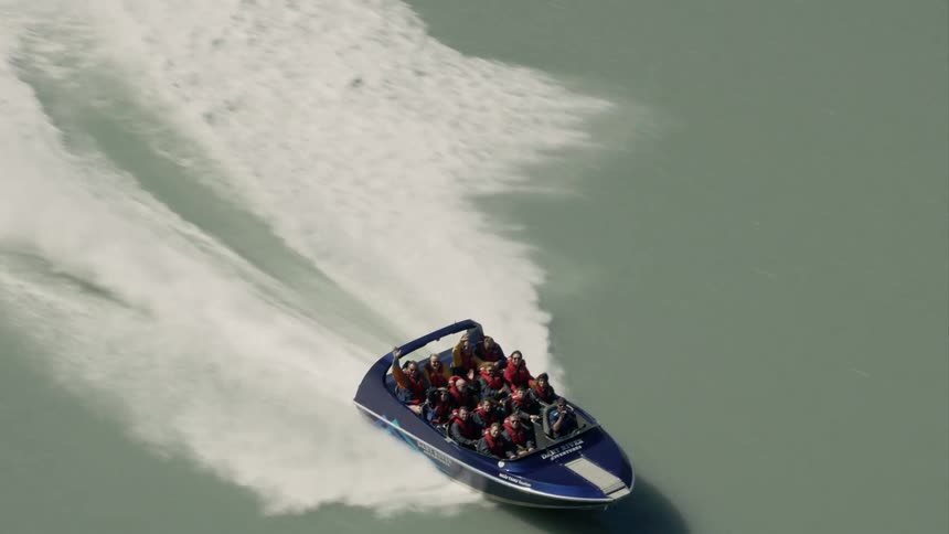 A speedboat filled with passengers zips through a body of water