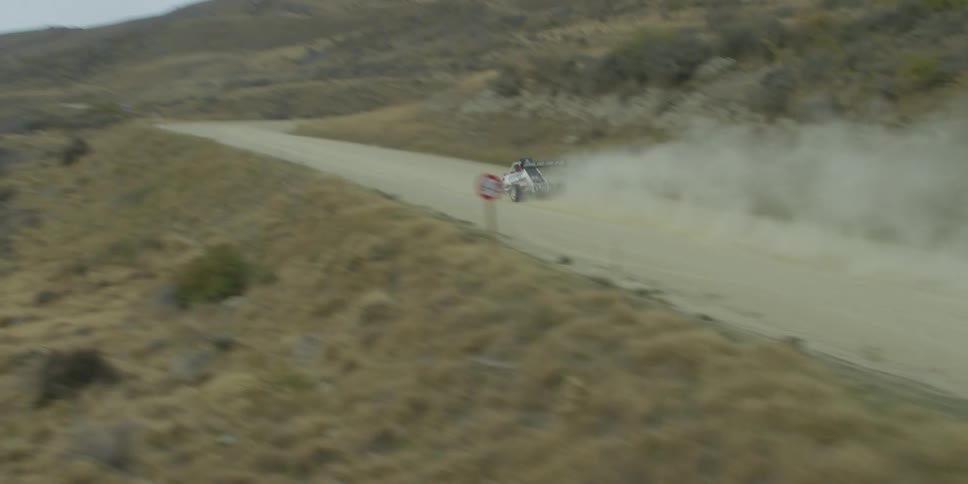 A racing vehicle flies down a dirt road in a desert