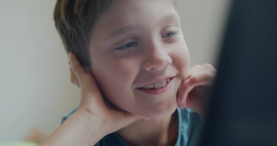 A male child smiles while rubbing his hands on his face