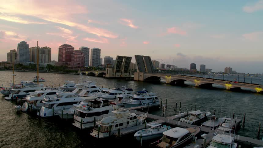 A marina filled with boats near a bridge and downtown area