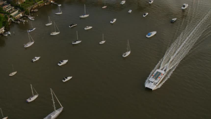 A motorboat moves through a waterway filled with sailboats Sydney Harbour