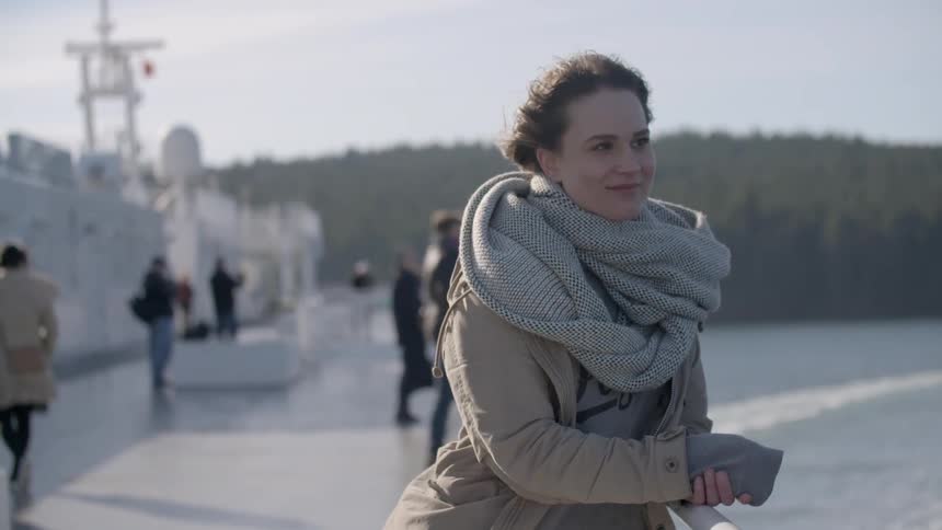 Woman standing and smiling on a ship on a windy day