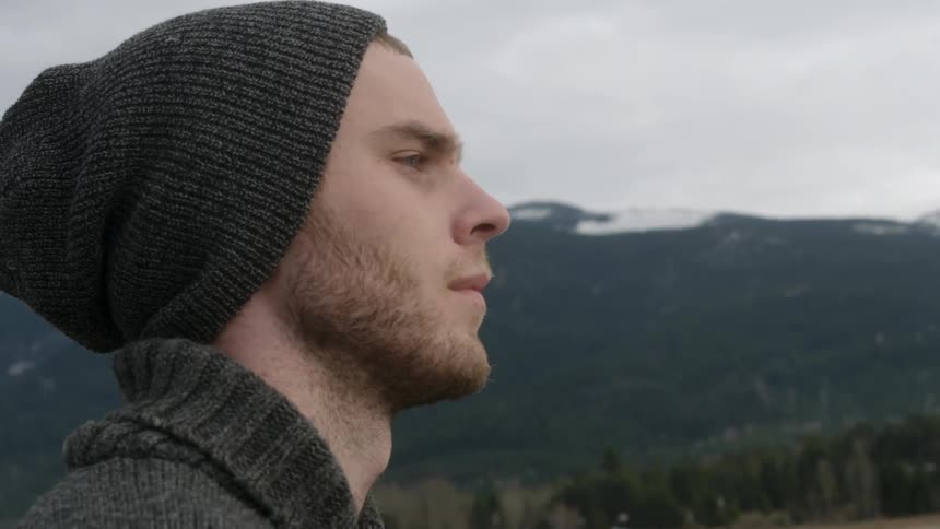A man is standing outside looking over a mountain range