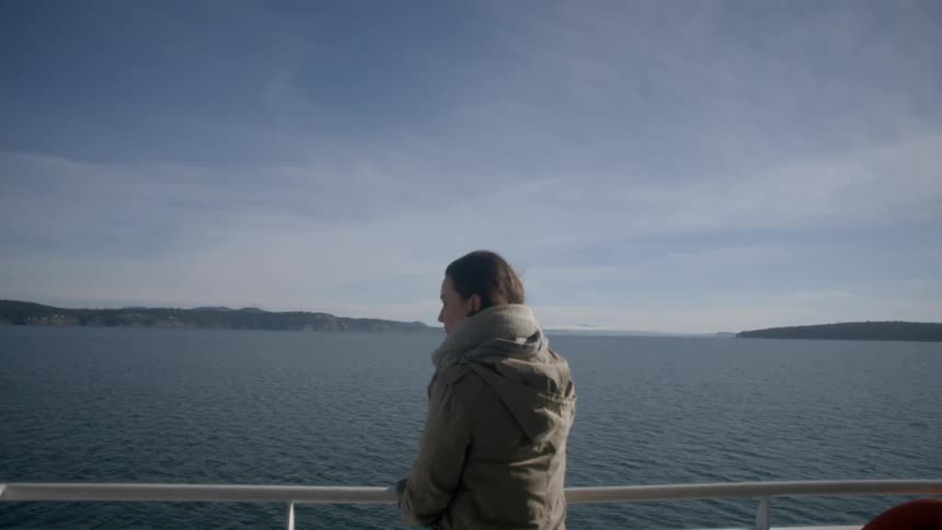 A woman is standing by the railing watching the water