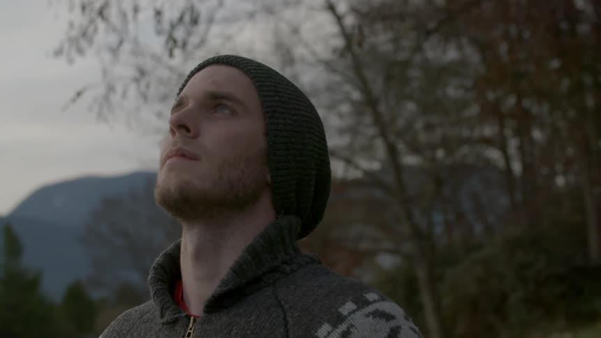 A man is standing outside looking up at a cloudy sky
