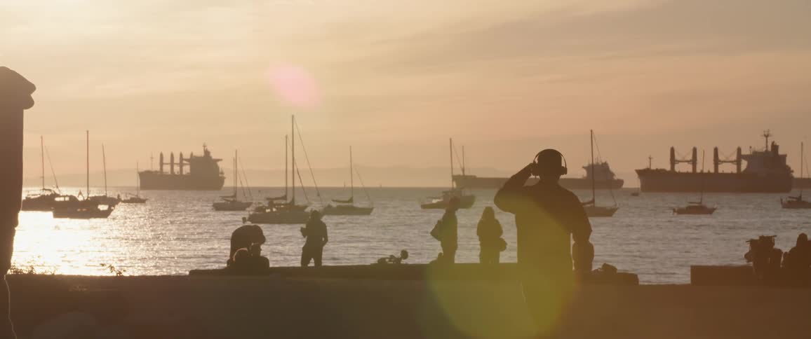 People relaxing on pier next to the ocean at sunset