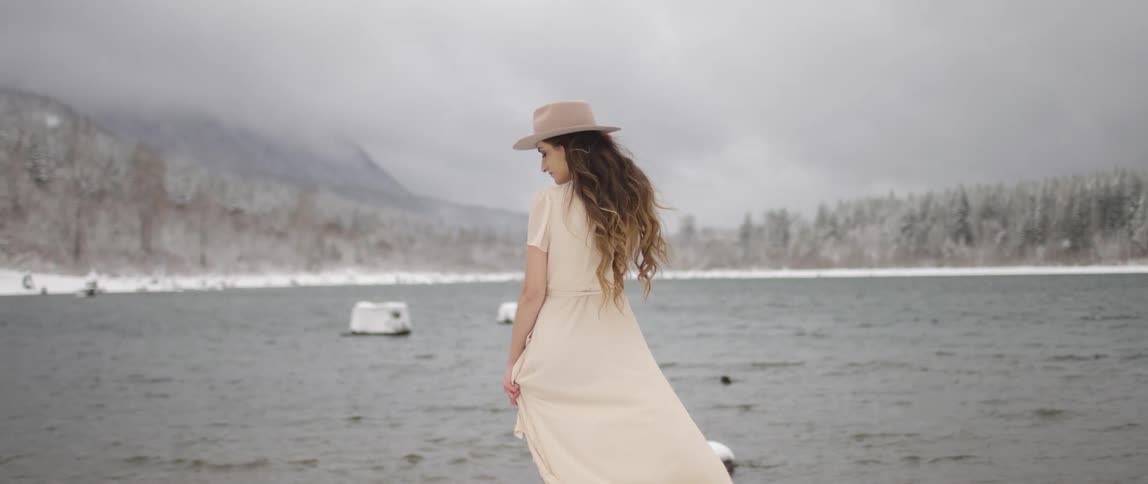 A woman stands by the lake in the snow