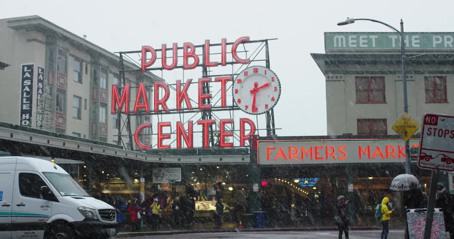 People walk and mill about outside a Seattle farmers market