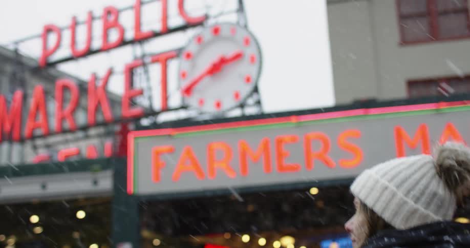 Woman walks up to the public market while it snows