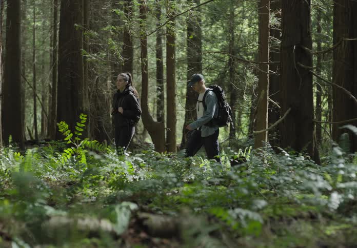 A man and woman are hiking through a forest