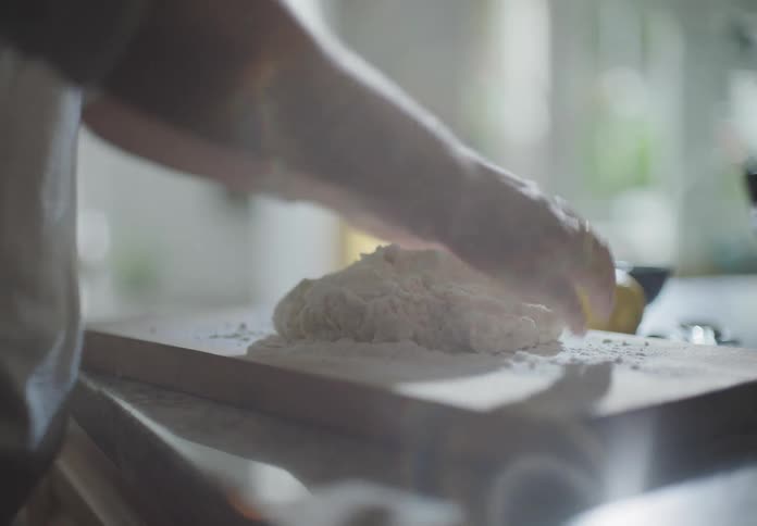Woman spreads flour on table to knead dough