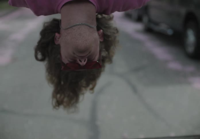 Teenage boy hangs upside down as he travels down the street