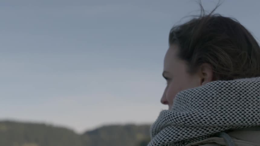 A scarfed woman stands outside on a breezy day