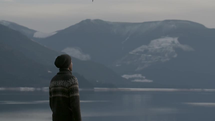 A man is walking over to a railing by a lake