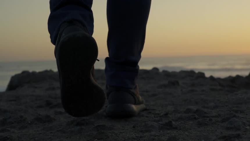 A person is walking along rocks by the shore