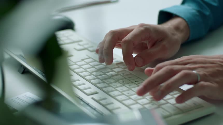 A white male types on a computer keyboard