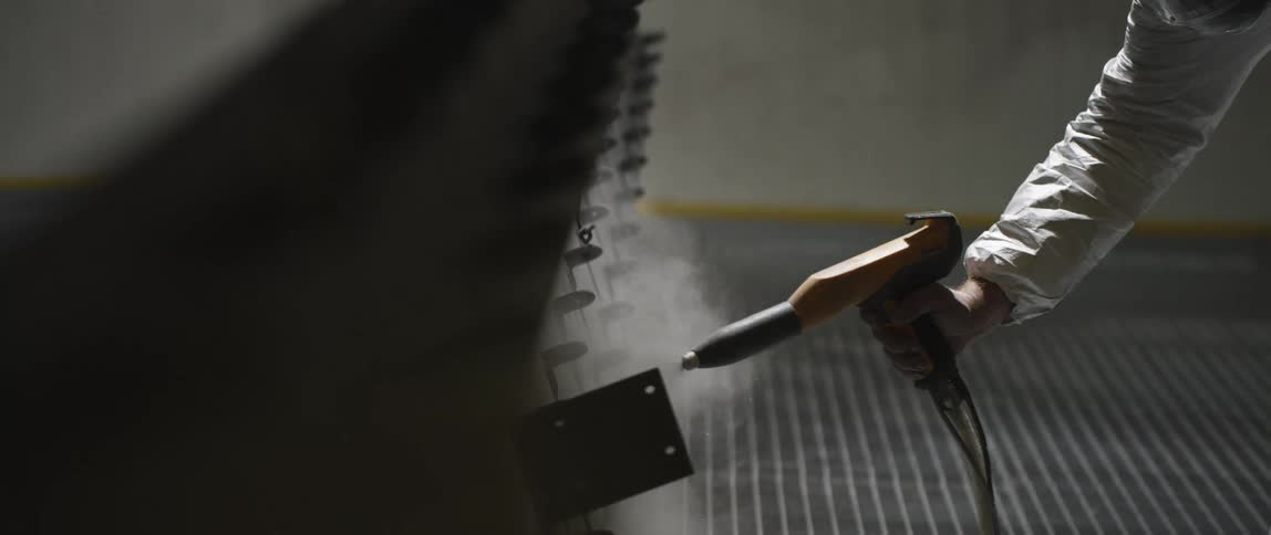 A white person in protective gear uses a spray to put a mist on a machine