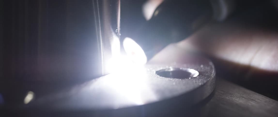 A flashlight sits against a piece of metal with a drill hole in it