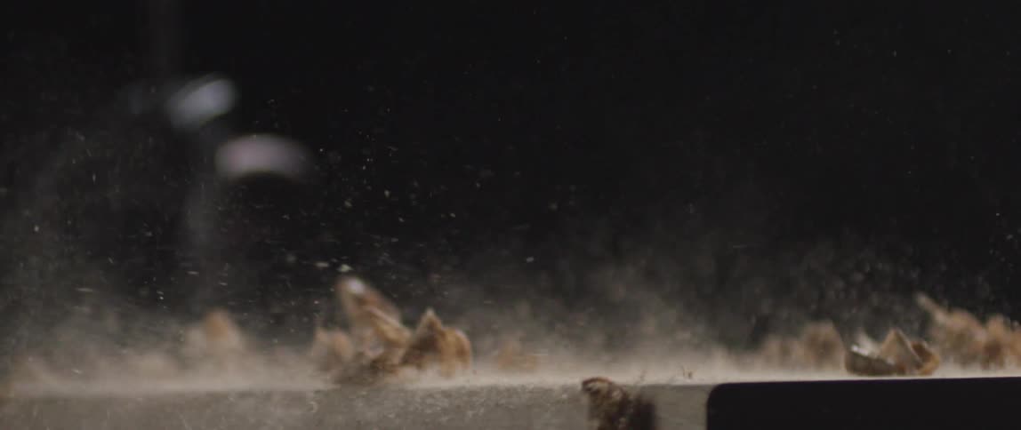 Sawdust and wood curls are blown off a wooden board