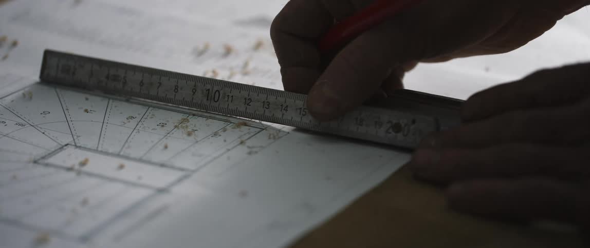 A man measures a sketch on a blueprint in an office