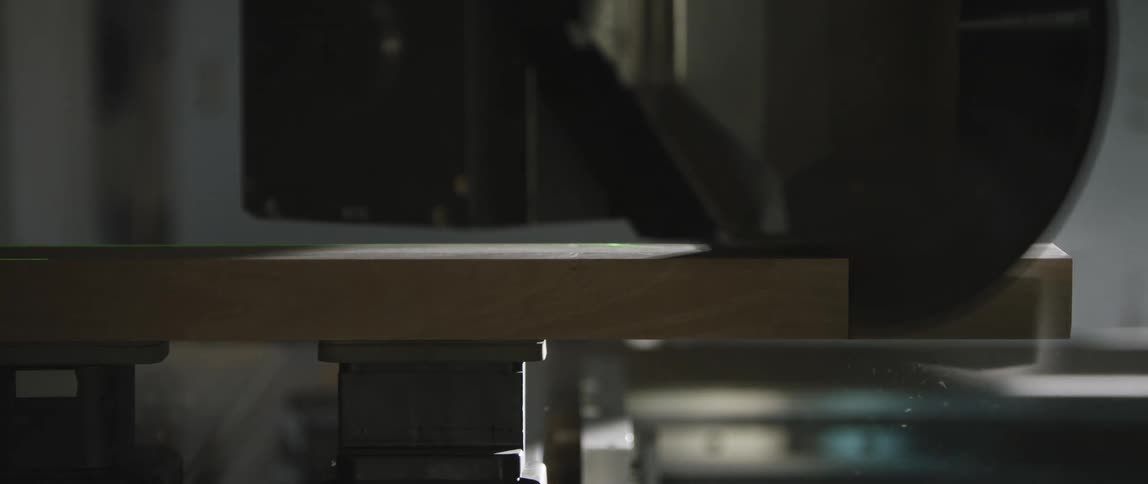 A circular saw blade cuts through a piece of wood
