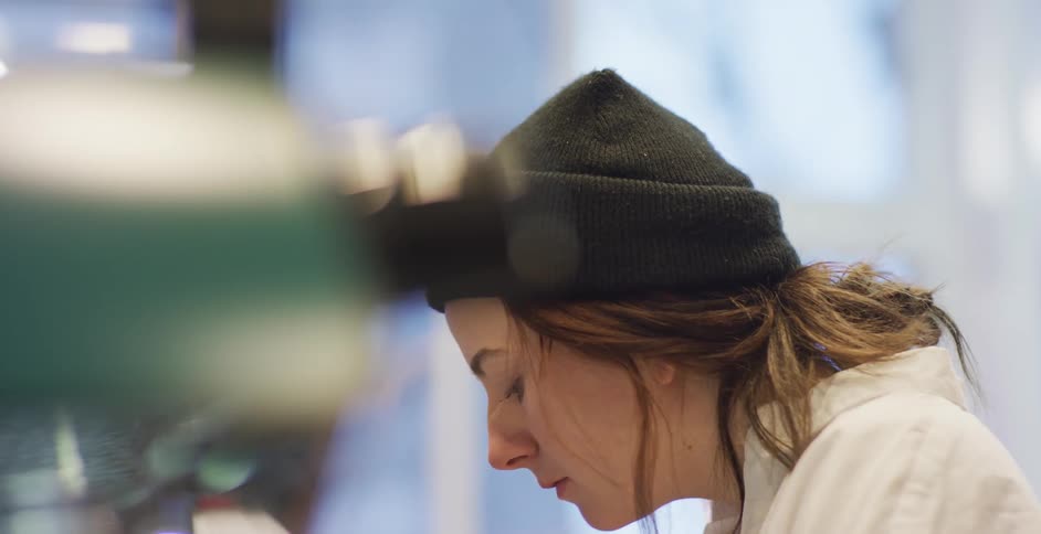 A white woman in a coat and hat works in a lab