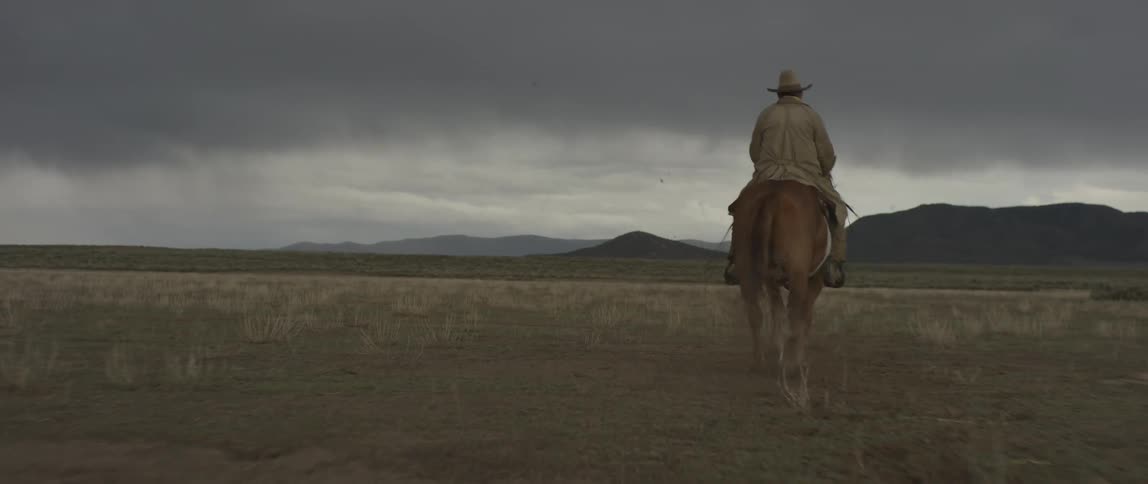 A man rides his horse across the prairie