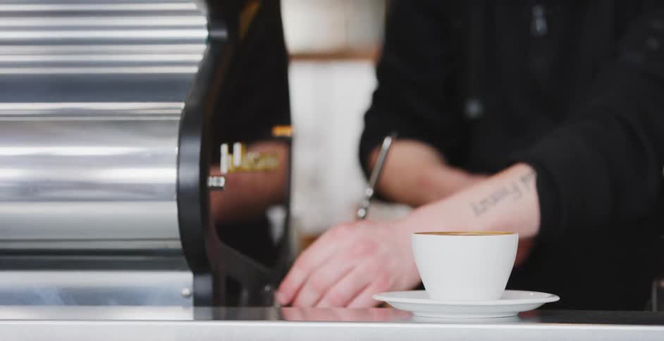 A person placing a coffee drink on a saucer and putting a spoon next to it