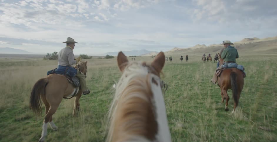A group of men ride horses through a pasture
