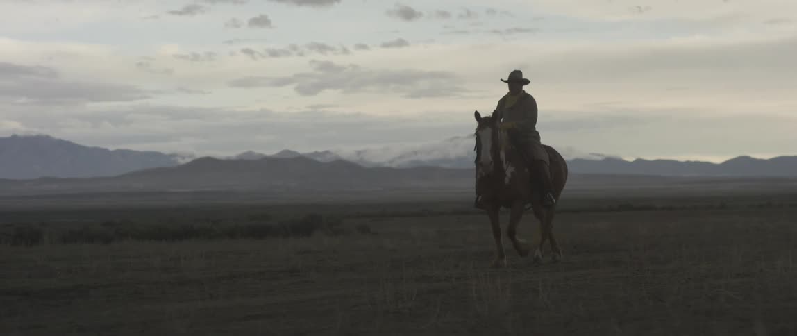 A man is riding a horse in a rural area