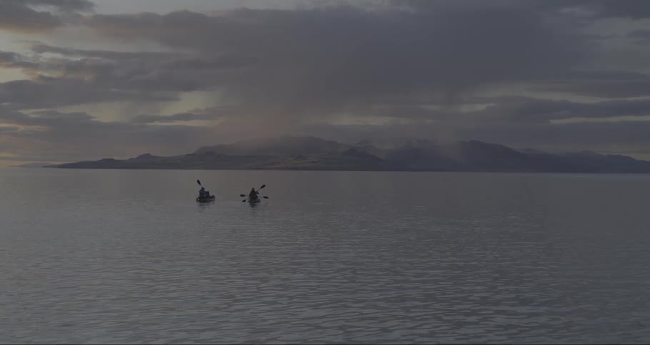 Family paddles canoes across the lake at dusk