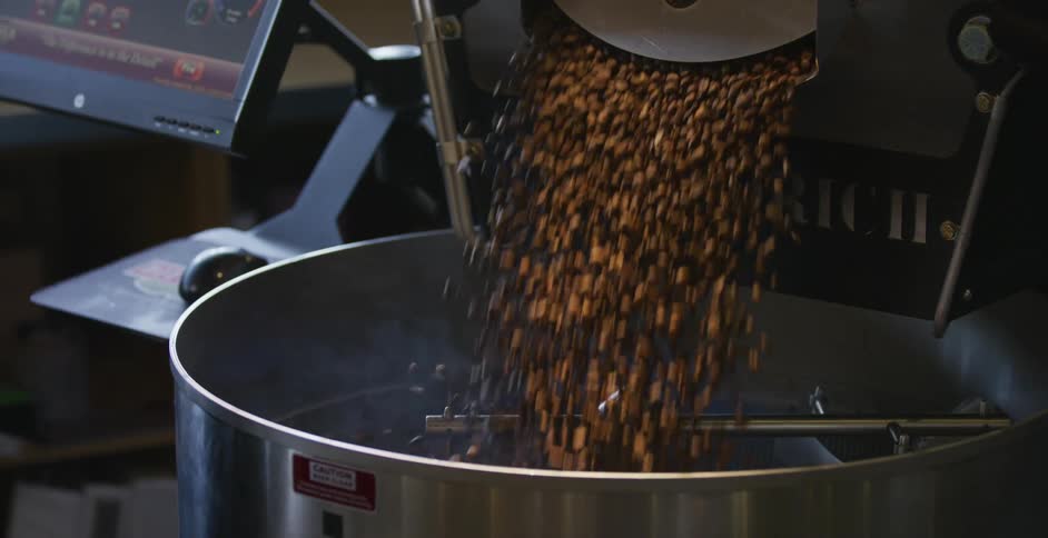 Coffee beans spill out of a container and into a mixer
