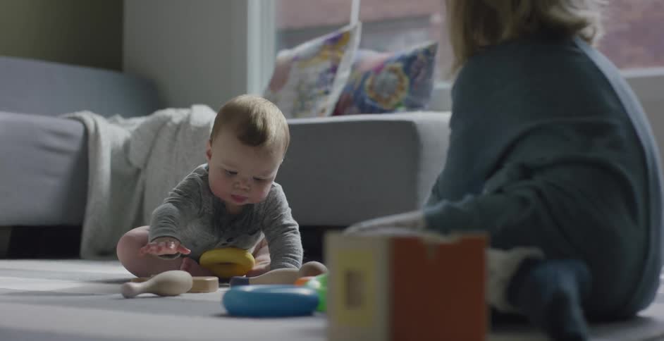 A young girl and a baby play with toys on the floor of a living room