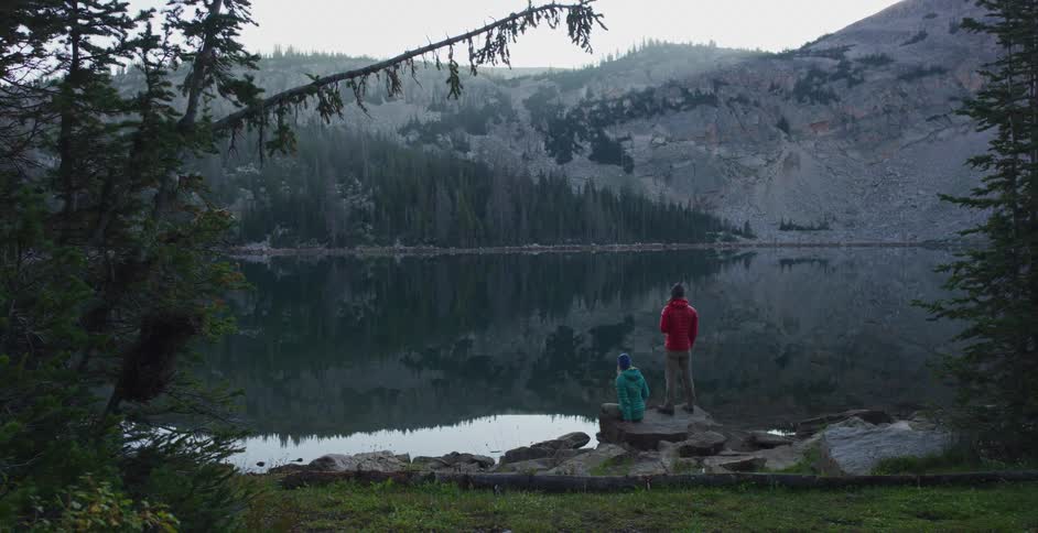Two people are outdoors looking at the mountains