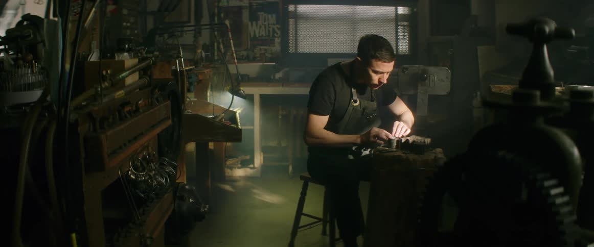 A young man working as a jeweler examines a piece