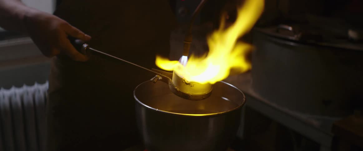 Man uses blowtorch to melt metal in crucible