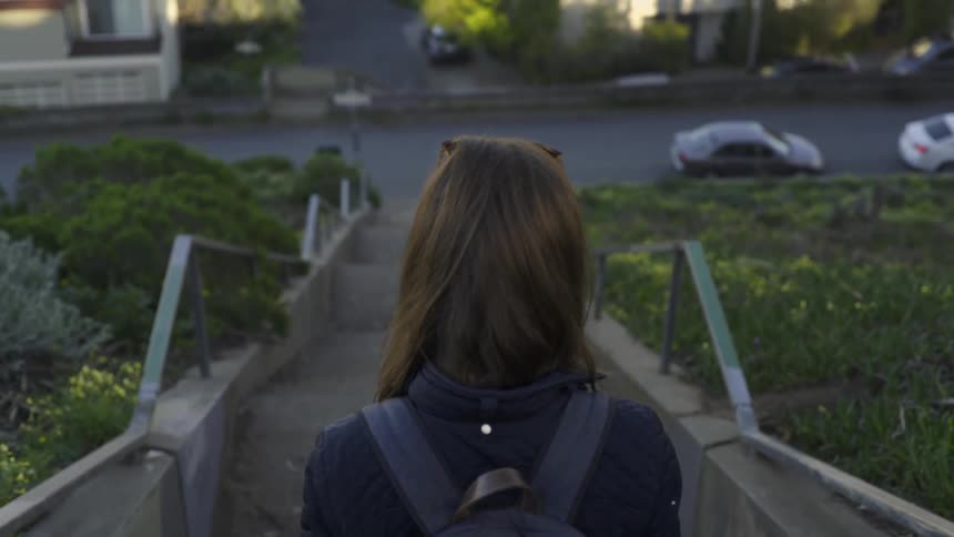 A woman is walking down steep steps in a town