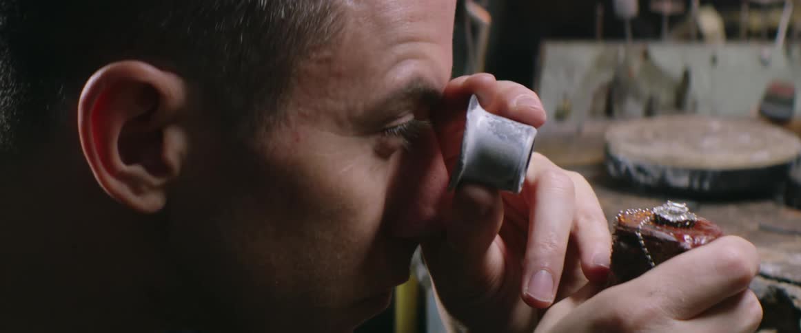 A young man examines a gem