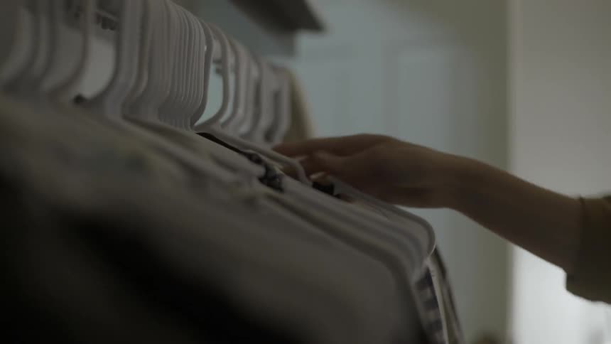 A person is placing clothing on a rack
