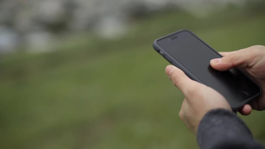 Person standing on grass using smartphone outdoors with calm everyday vibe.
