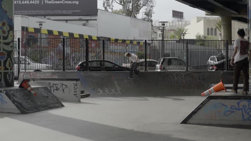 Man in white outfit doing skatepark tricks with confident energetic style.