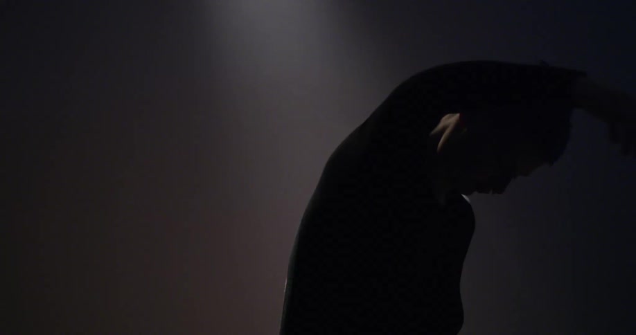 A male dancer moves through shadow and light