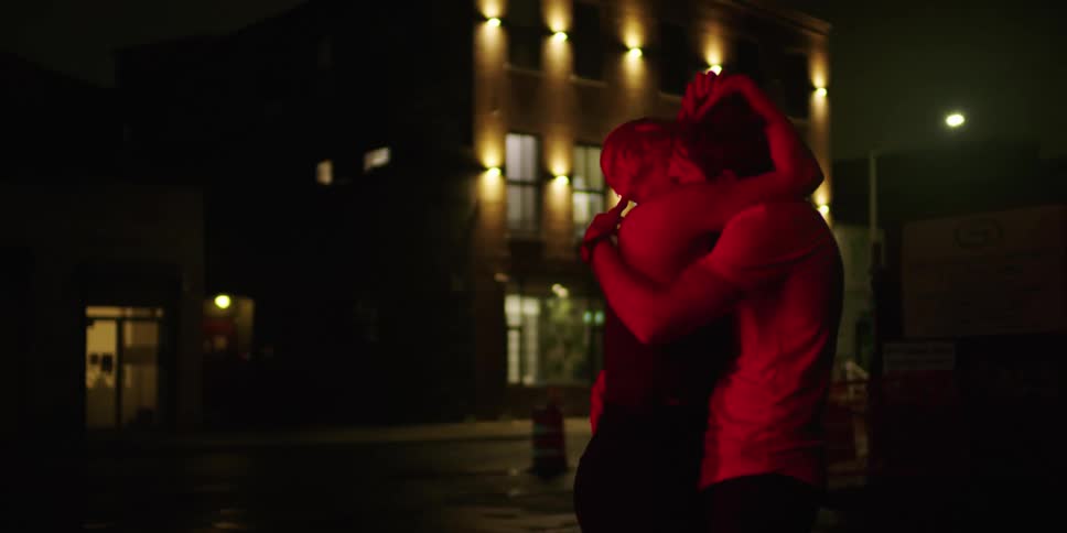 Two people are dancing outdoors at night