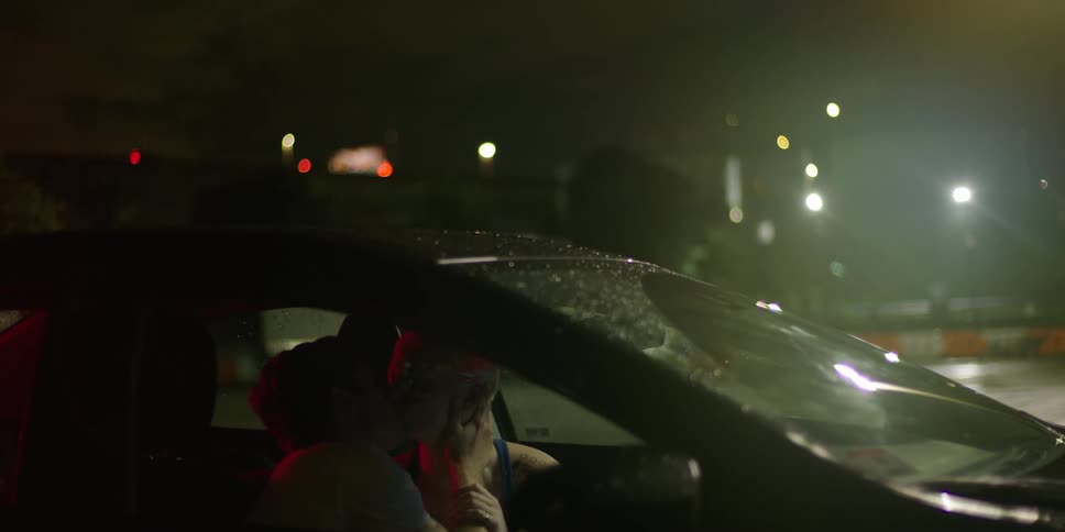 Romantic couple making out inside car at night at a parking lot