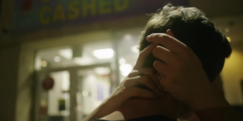 Woman strokes mans hair then kisses him near storefront
