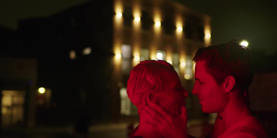 A man and woman are kissing outside in the dark