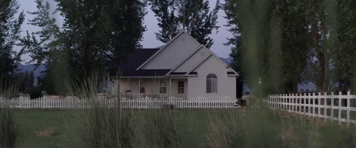 A small house with a white picket fence with a large yard